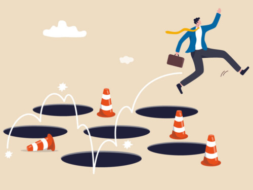 businessman jumping around holes and construction cones